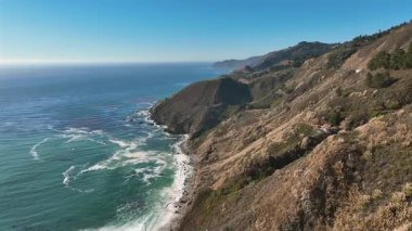 Drone View of Big Sur Cliffs Overlooking the Pacific Ocean in Big Sur, California, USA on July 4, 2025: Scenic Pacific Coast Highway 1 with Cars on Road, Mountains, and Boats in the Distance