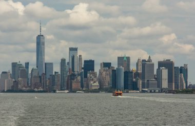 New York şehrinin ikonik gökdelenleri ve nehir boyunca giden bir feribotla nefes kesici bir görüntüsü. Sahne şehrin dinamik ve canlı atmosferini yakalıyor..