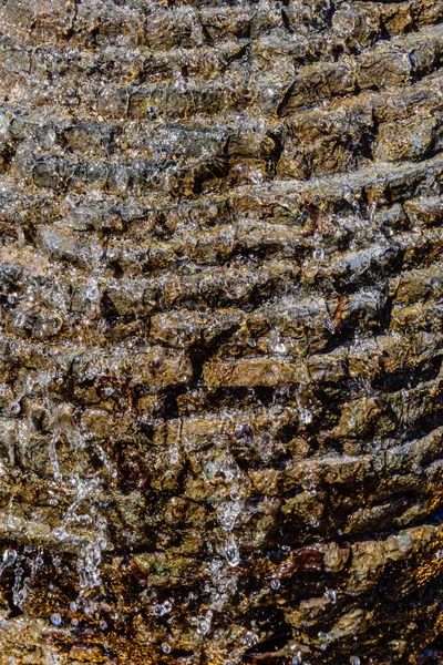 Steinmauerwerk mit fließendem Wasser, das mit Wasserschaum nach unten fließt. — Stockfoto