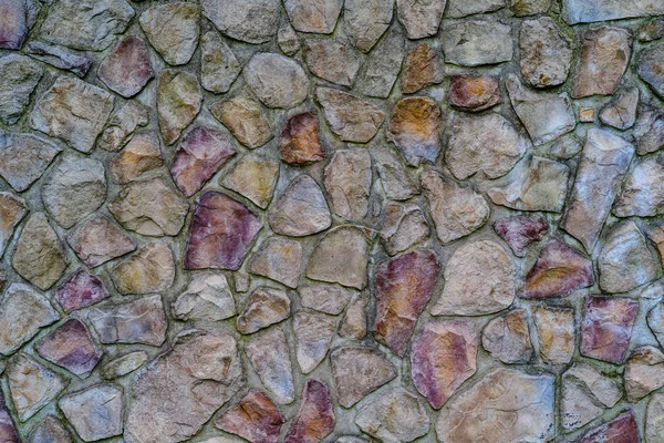Vägg av färgade stenar fästa med cement, bakgrund. — Stockfoto