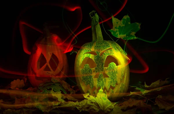 Luminous pumpkins in the dark for the autumn Halloween holiday. Jacks grinning head. Magical bright neon green and red light in the darkness of Freezelight. All Saints Day — Stock Photo, Image