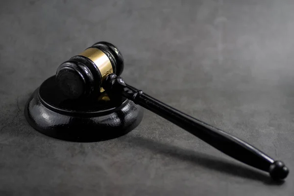 Hakimin ahşap tokmağının yakın plan, düşük açılı bir çekimi, altın bir bantla, grev bloğunda dinleniyor..