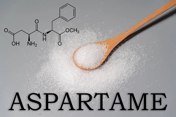Yüzeye dağılmış beyaz kristal tozlu bir kaşık (aspartam), kimyasal yapısı ile kaplıdır..