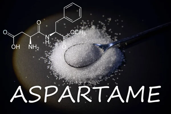 Yüzeye dağılmış beyaz kristal tozlu bir kaşık (aspartam), kimyasal yapısı ile kaplıdır..