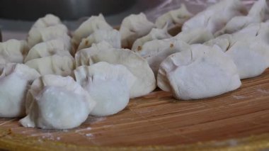 Örülmüş bir hasırın üzerinde duran el yapımı hamur köftesinin (muhtemelen pişirilmemiş veya buharlaşmamış) yakın çekimi..