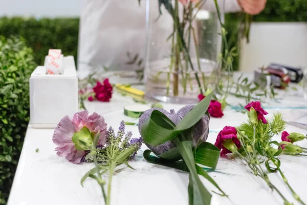 Floristics çiçekçi cam vazo ile masada döşeme çiçeklenir