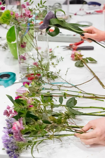 Floristics çiçekçi cam vazo ile masada döşeme çiçeklenir
