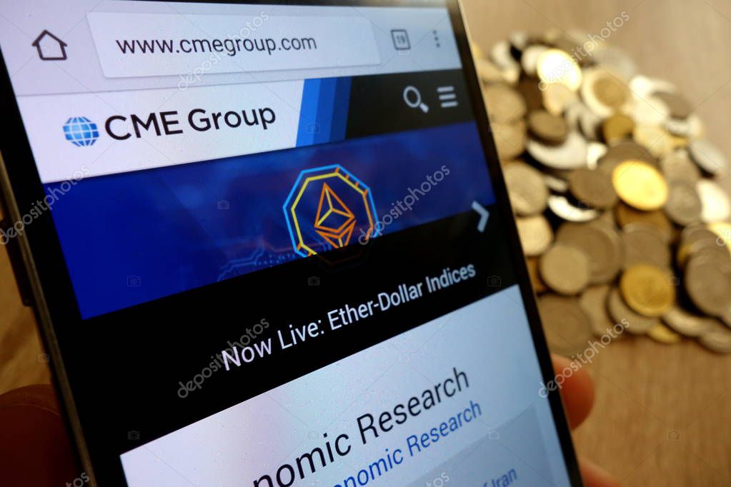 KONSKIE, POLAND - MAY 14, 2018: CME Group website displayed on smartphone and stack of coins
