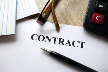 Kalem, hesap makinesi ve masa üzerine gözlük ile sözleşme belge