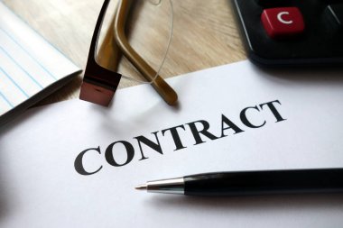 Kalem, hesap makinesi ve masa üzerine gözlük ile sözleşme belge