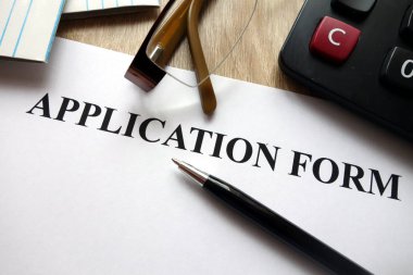 Kalem, hesap makinesi ve masa üzerine gözlük ile başvuru formu