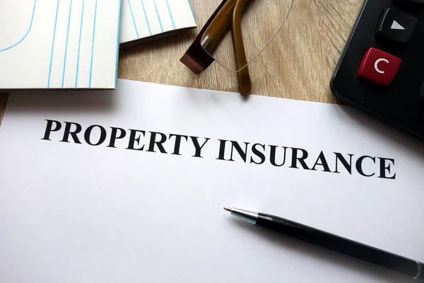 Property insurance document with pen, calculator and glasses on desk