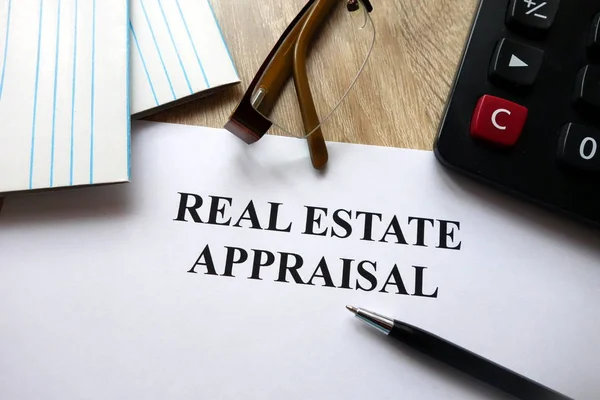 Real estate appraisal document with pen, calculator and glasses on desk
