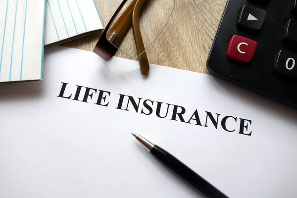 Life insurance document with pen, calculator and glasses on desk