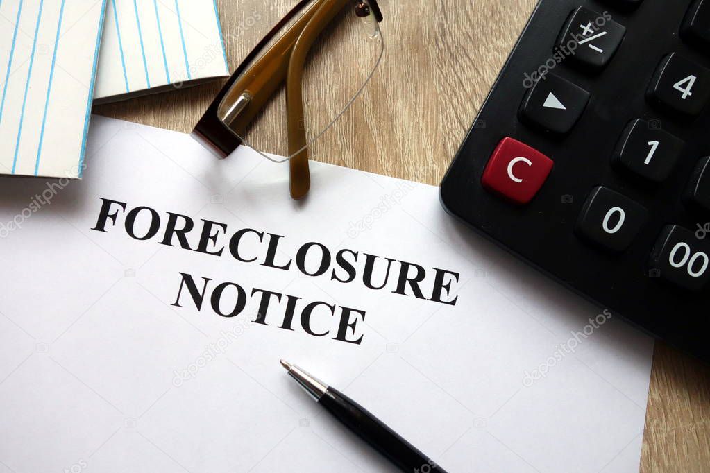 Foreclosure notice with pen, calculator and glasses in office