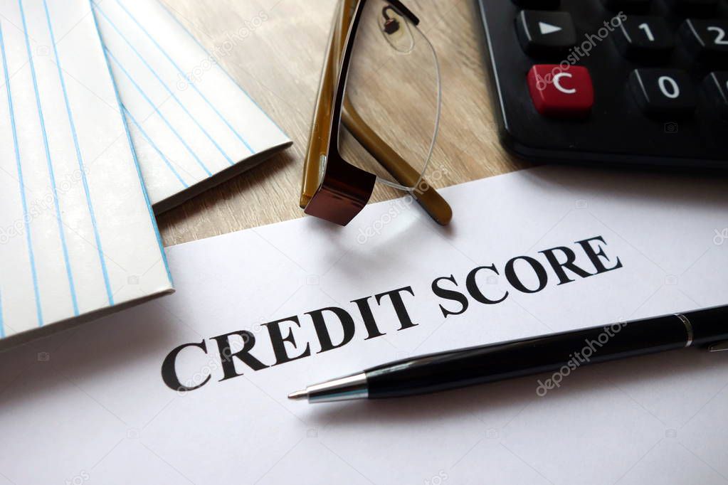 Credit score document with pen, calculator and glasses on desk