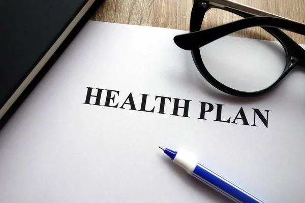 Health plan form, pen and glasses on desk