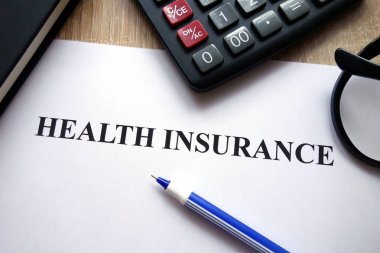 Sağlık sigortası belge, hesap makinesi, kalem ve gözlük üstünde okul sırası