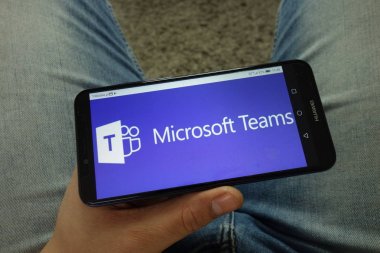 Konskie, Polonya - 13 Nisan 2019: Microsoft Teams iletişim platformu logosu ile akıllı telefon tutan adam