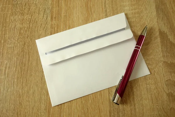 White envelope and pen on a wooden background — ストック写真