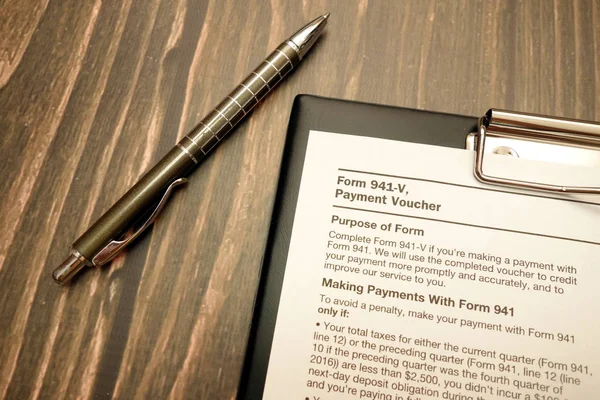 Form 941-v, payment voucher and pen on wooden desk