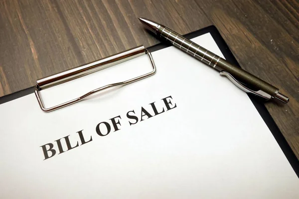 Clipboard with bill of sale and pen on desk