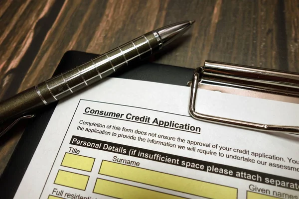 Urklipp med konsumentkrediter ansökan och penna på skrivbordet — Stockfoto