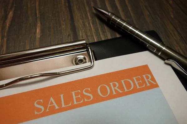 Clipboard with sales order and pen on desk