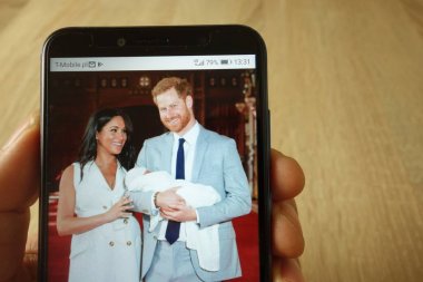 Konskie, Polonya - 18 Mayıs 2019: Prens Harry ve Meghan Markle'ın bebekli fotoğrafıyla el ele akıllı telefon