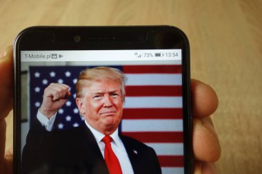 Konskie, Polonya - 18 Mayıs 2019: Donald Trump'ın amerikan bayrağıyla çekilmiş fotoğrafı yla el ele akıllı telefon