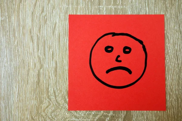 Сумне нещасне обличчя намальоване на червоній наклейці — стокове фото