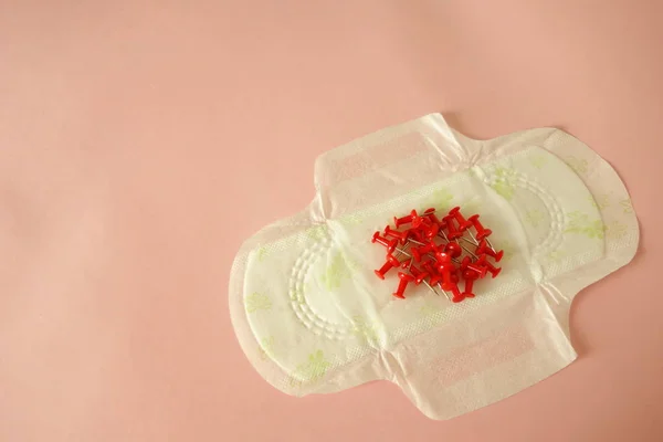 Almofada menstrual com pinos vermelhos no fundo rosa, espaço de cópia para o seu design — Fotografia de Stock
