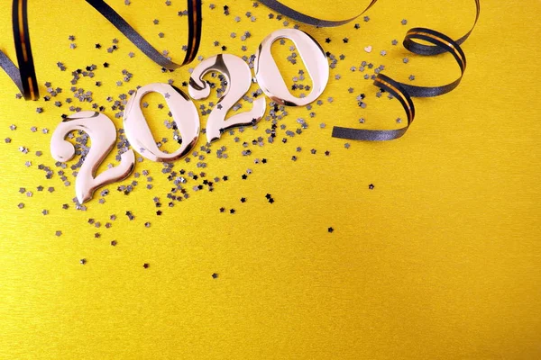 Número dorado 2020 y decoraciones sobre fondo amarillo —  Fotos de Stock