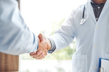 Kendine güvenen Doktor hastanede hasta konuşma ile el sıkışan