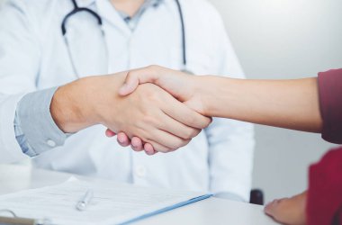 Kendine güvenen Doktor hastanede hasta konuşma ile el sıkışan