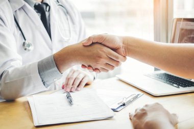 Kendine güvenen doktor hastane ofiste hasta konuşma ile el sıkışan