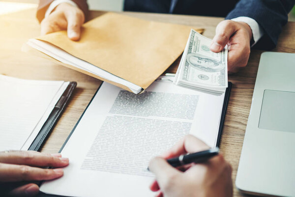 Концепция коррупции, бизнесмен передает деньги долларовые купюры коррупционному подкупу бизнесмену-менеджеру
