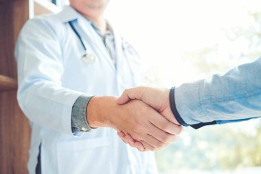 Kendine güvenen Doktor hastanede hasta konuşma ile el sıkışan