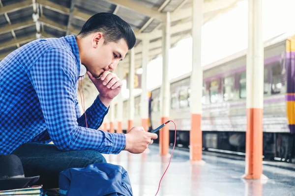 Seyahat telefon dinleme müzik telefonu kullanan adam ve tren istasyonunda
