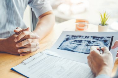 Erkek hastaya konuşuyor ve sonuçlarını diş üzerinde sunan diş hekimi