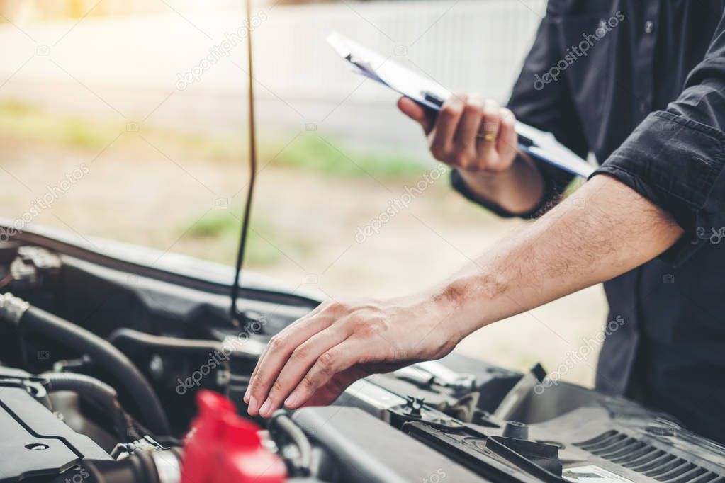 Auto mechanic working in garage Technician holding clipboard and