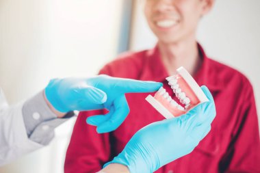 Dişçi gülümseyen erkek hasta ve gösteren protez konuşuyor d