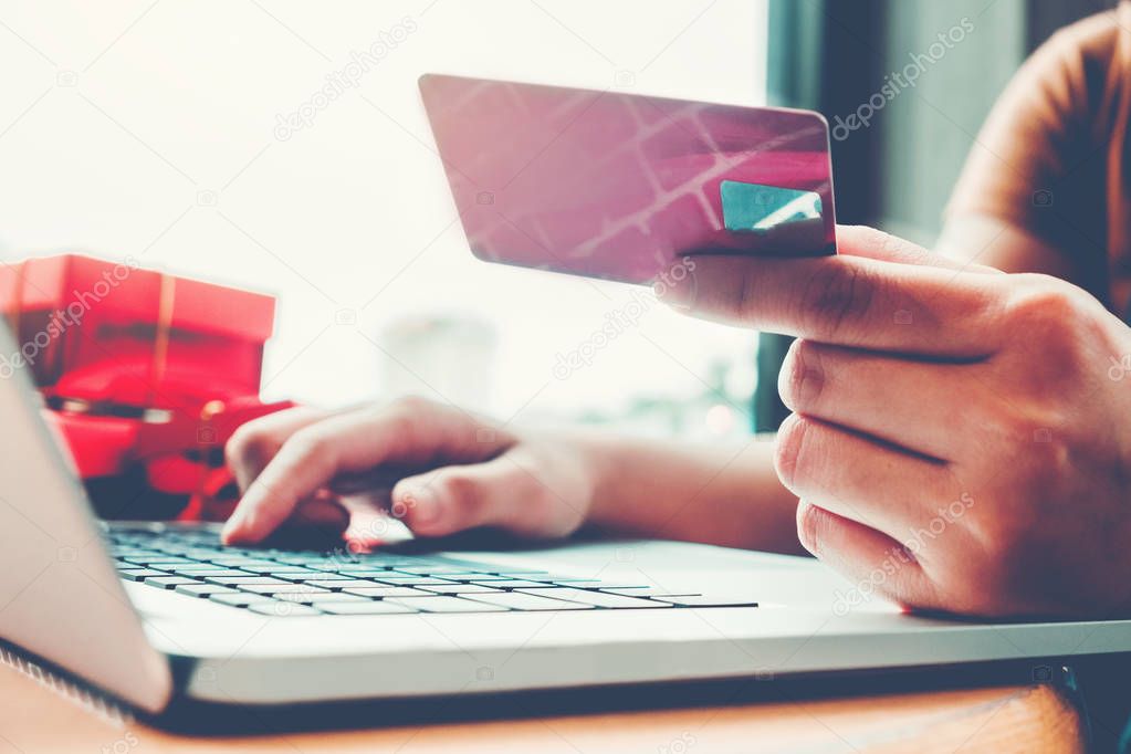Woman with laptop shopping online with debit card in cafe