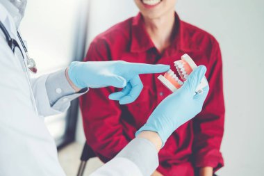 Dişçi gülümseyen erkek hasta ve gösteren protez konuşuyor d