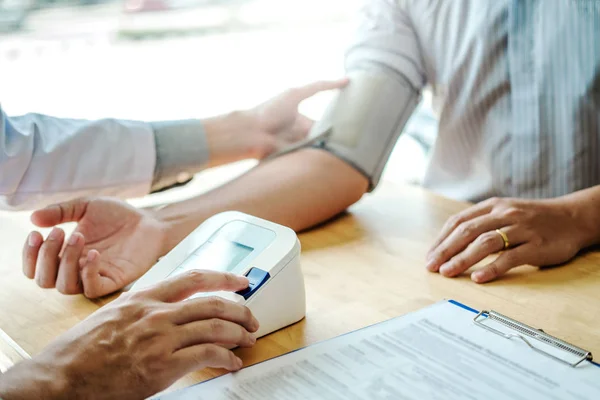 Doctor Measuring arterial blood pressure man patient on right ar — Stock Photo, Image