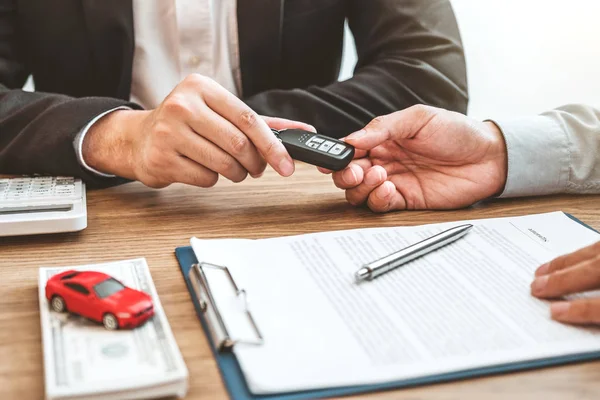 Verkäufer gibt Autoschlüssel an Kunden und unterschreibt Vertrag — Stockfoto