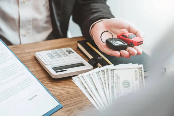 Verkäufer gibt Autoschlüssel an Kunden und unterschreibt Vertrag — Stockfoto