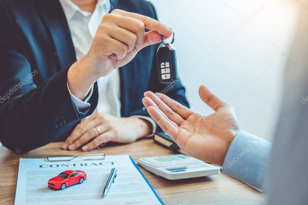 Sale agent giving Car key to customer and sign agreement contrac