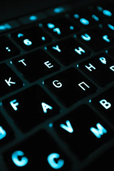 Macbook keyboard Russian letters symbols, macro view, glowing in a dark.