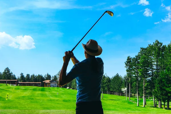 Yeşil çim sahada güneşli havalarda golf oynarken bir kovboy şapkalı adam siluet.